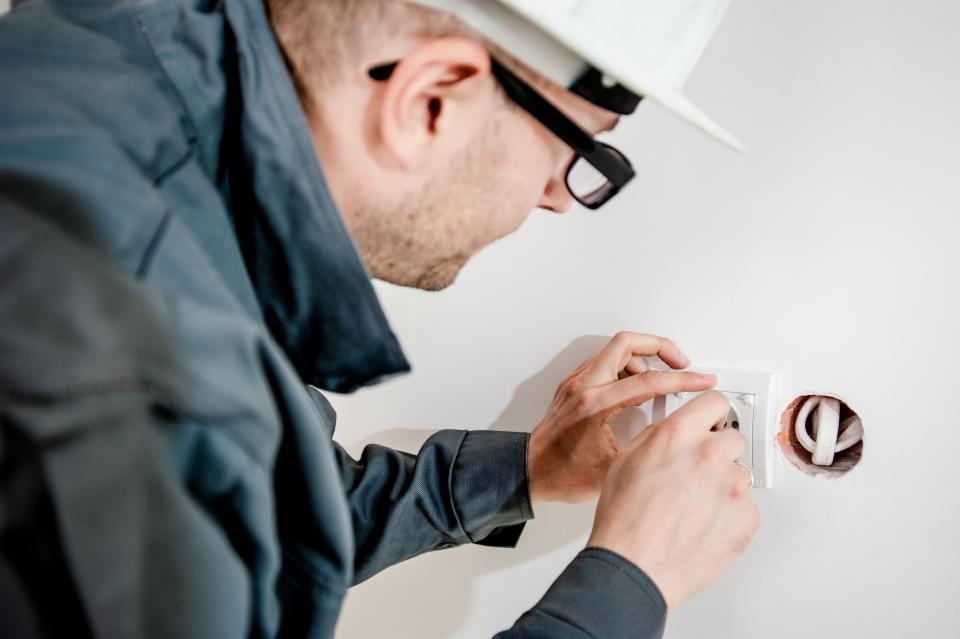An electrician in a hard hat fitting a power point