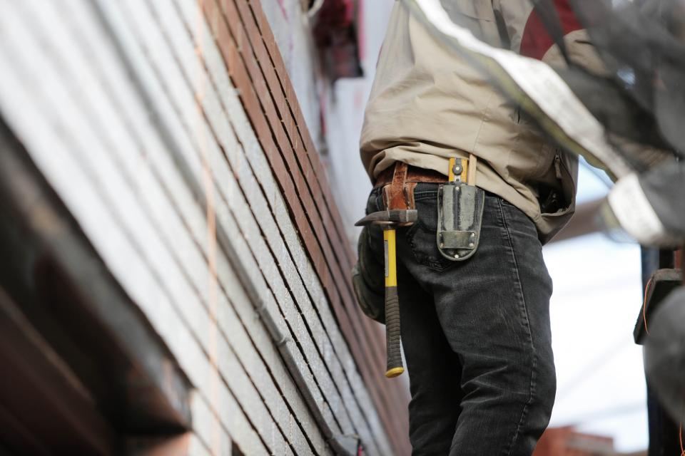 A tradie with a hammer and tape measure on their tool belt